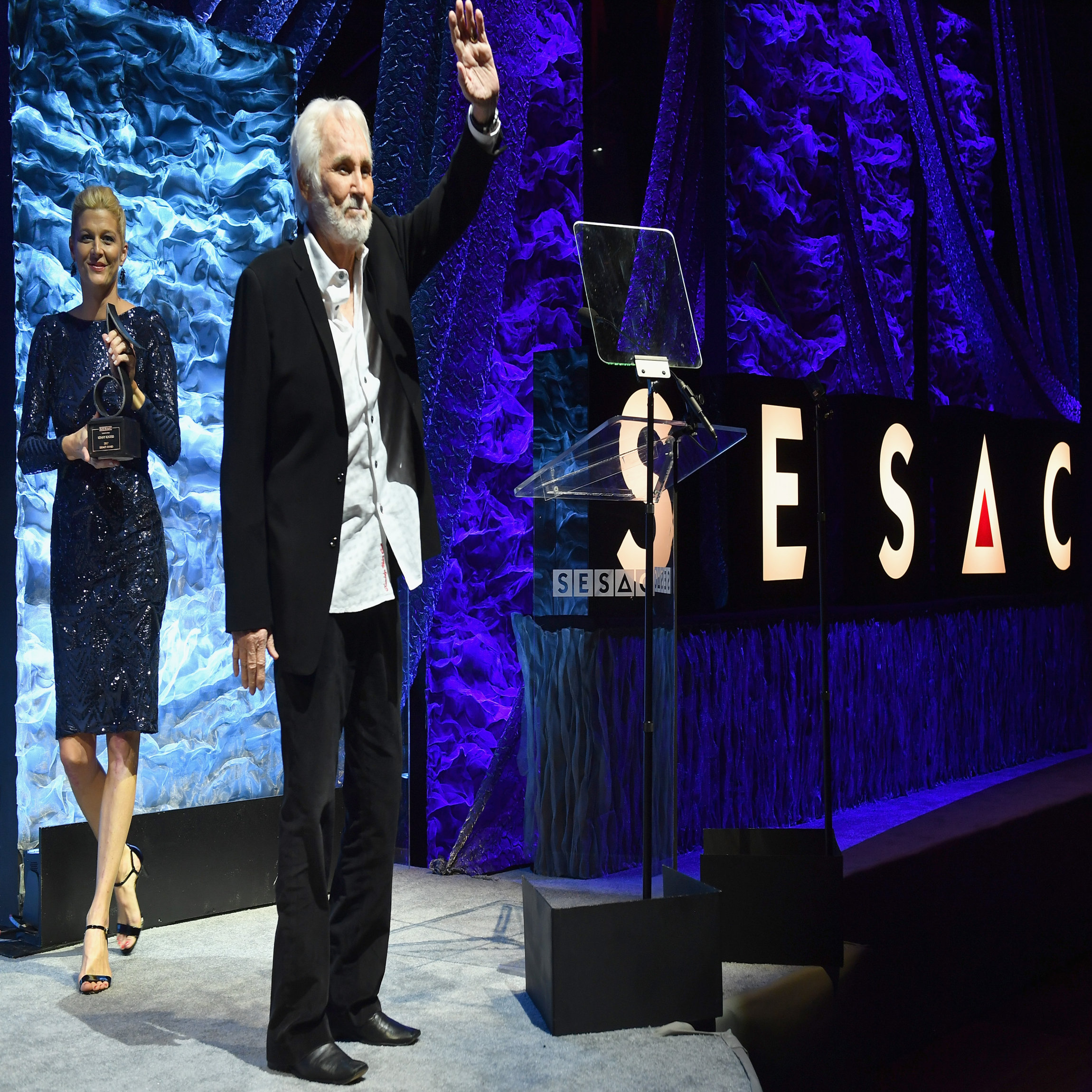 NASHVILLE, TN - NOVEMBER 05: Vice President of Creative Services for SESAC Shannan Hatch and Legacy Award recipient Kenny Rogers stand onstage during the 2017 SESAC Nashville Music Awards on November 5, 2017 in Nashville, Tennessee. (Photo by Jason Davis/Getty Images for SESAC)