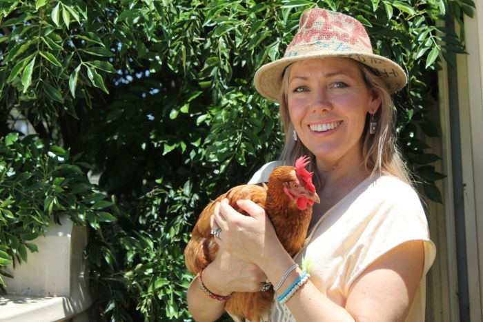 Saturday Night Country host Felicity Urquhart holds a chicken on a farm.