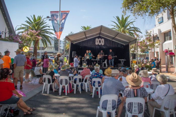 A crow sits around a stage sporting the ABC logo where a band is playing for a live broadcast