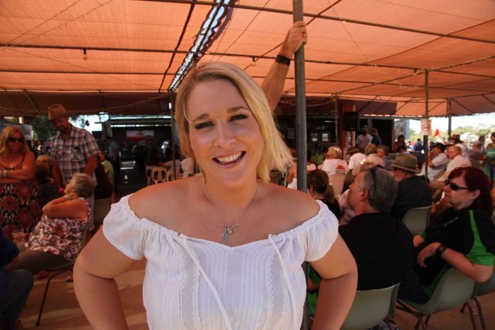 A woman smiles at the camera standing in front of a crowd.