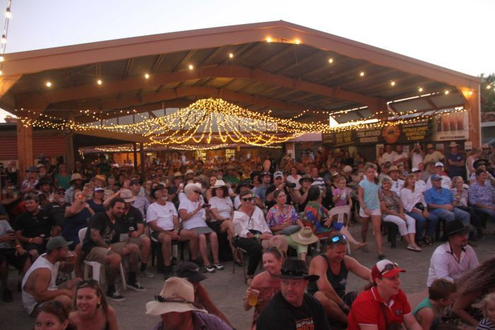 a crowd of people in a shed under fairy lights